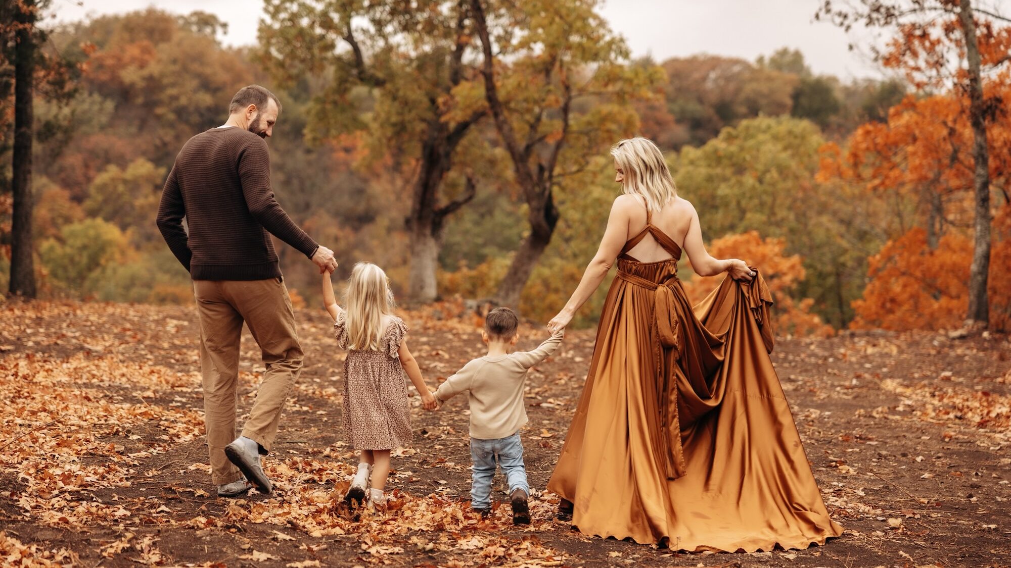 family of 4 walking in wooded area during the fall